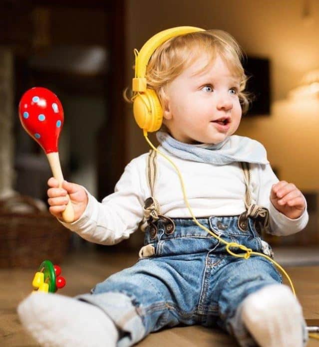 Apartments in Northwest Houston North A baby wearing headphones and playing with a maraca in Apartments for rent in NW Houston North.